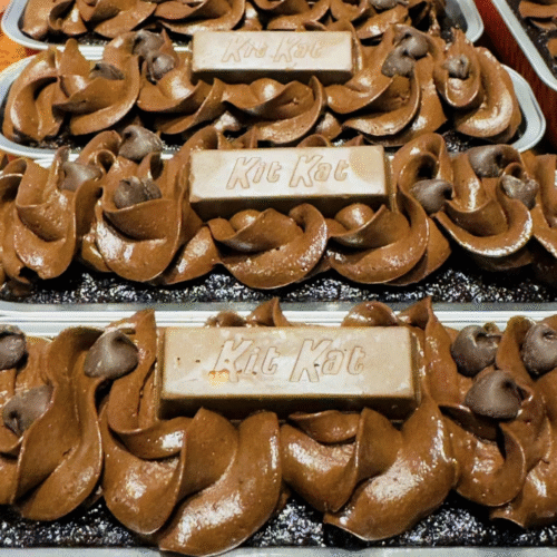 Moist chocolate mini loaf cakes decorated with chocolate frosting and Kit Kat bars on a wooden board.