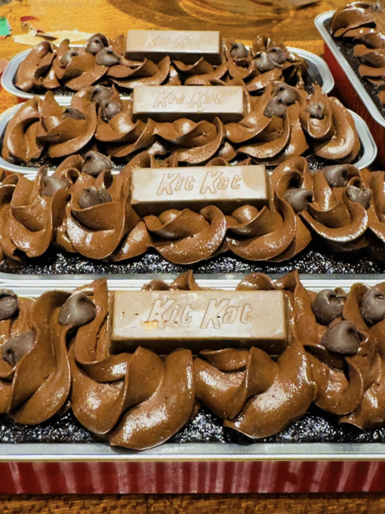 Moist chocolate mini loaf cakes decorated with chocolate frosting and Kit Kat bars on a wooden board.