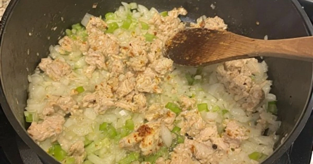 Flat lay of raw ingredients for chicken corn chowder including diced chicken, corn kernels, potatoes, cream, onions, and celery on a kitchen counter. 