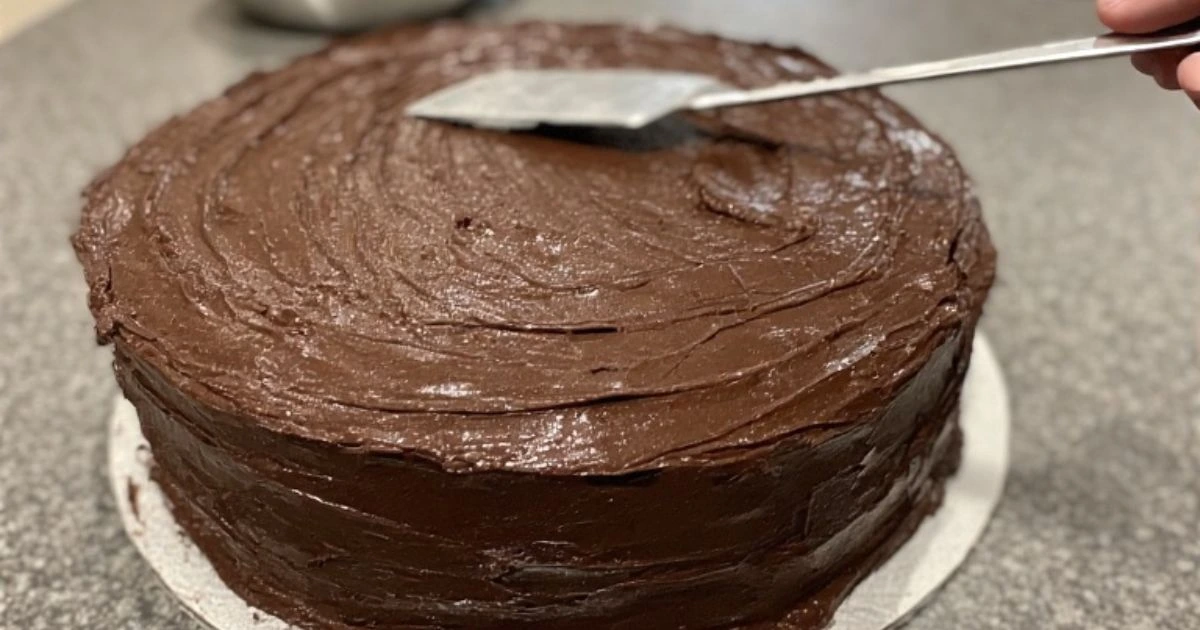 Decorating an easy chocolate cake recipe with rich, creamy chocolate frosting.